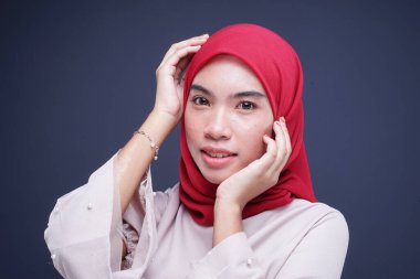Krem rengi, modern kebaya rengi kırmızı tesettürlü güzel bir Müslüman kadın modelin portresi. Gri arka planda izole edilmiş Asyalı Müslüman geleneksel bir elbise. Eidul Fitri moda ve yaşam tarzı portresi konsepti.