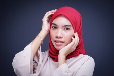 Krem rengi, modern kebaya rengi kırmızı tesettürlü güzel bir Müslüman kadın modelin portresi. Gri arka planda izole edilmiş Asyalı Müslüman geleneksel bir elbise. Eidul Fitri moda ve yaşam tarzı portresi konsepti.