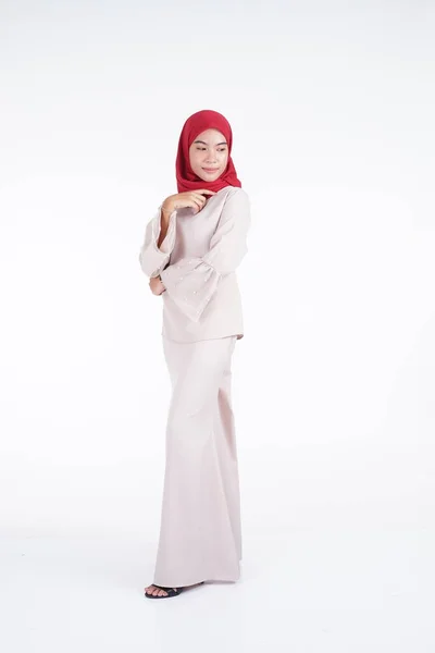 白を基調としたアジア系ムスリムの伝統衣装 赤ヒジャーブ を着たクリーム色のモダンなケバヤを着た魅力的なムスリム女性モデル Eidul Fitriファッションとライフスタイルの肖像コンセプト — ストック写真