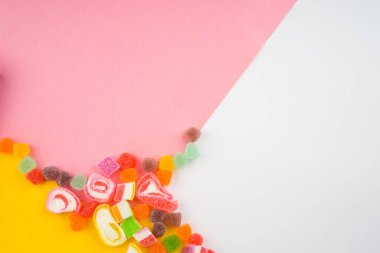 Renkli şekerlerin ve pastel arka planda tatlıların yaratıcı düzenlemesi. Düz görünüm.