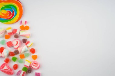 Renkli şekerlerin ve pastel arka planda tatlıların yaratıcı düzenlemesi. Düz görünüm.