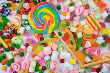 Beyaz arka planda renkli şeker ve şekerlerin yaratıcı düzenlemesi. Düz görünüm.