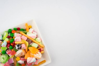 Beyaz arka planda renkli şeker ve şekerlerin yaratıcı düzenlemesi. Düz görünüm.