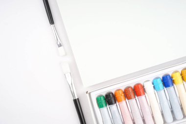 Okula dönüş konsepti. Kalem, kalem, suluboya ve diğerleri gibi kırtasiyelerin düz görünümü ışık arkaplan üzerinde yaratıcı olarak düzenlenmiştir.