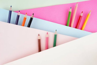 Okula dönüş konsepti. Kalem, kalem, suluboya ve diğerleri gibi kırtasiyelerin düz görünümü ışık arkaplan üzerinde yaratıcı olarak düzenlenmiştir.