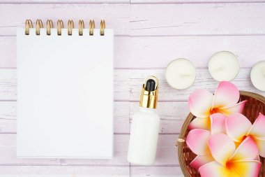 Frangipani çiçeklerinin yaratıcı düzenlemesi ve ahşap doku arka planında sarmal defter. Zen aromaterapi kavramı. Metin için dizüstü bilgisayara boşluk kopyala.