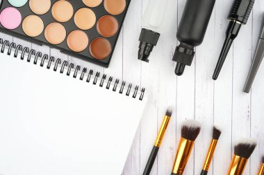 Açık renkli ahşap bir masanın üzerinde kozmetik aksesuarlar düzenleniyor. Güzellik ve kozmetik konsepti. Düz görünüm.