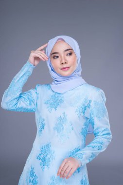 Gri arka planda izole edilmiş Müslüman kadınlar için kentsel bir yaşam tarzı olan, mavi, tesettürlü, tesettürlü güzel bir Müslüman kadın modeli. Güzellik ve tesettür moda konsepti. Yarım uzunluk