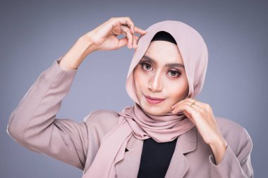 Gri arka planda izole edilmiş tesettürlü güzel bir Müslüman kadın modelin portresi. Başörtüsü ve Müslüman yaşam tarzı konsepti