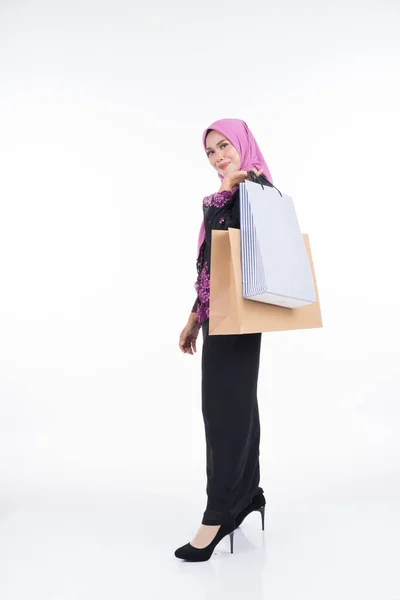 一位漂亮的亚洲女模特穿着传统的连衣裙 带着白色背景的购物袋 Eidul Fitri节庆准备购物概念 全长肖像 — 图库照片