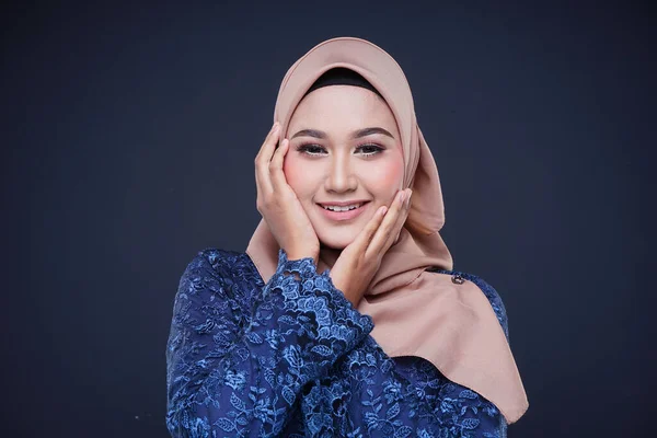 Closeup of a beautiful female Muslim model wearing dark blue modern kurung with hijab, a modern urban lifestyle apparel for Muslim women isolated on grey background. Beauty and hijab fashion concept.