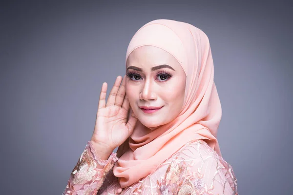 Headshot of a beautiful Muslim female model in an Asian Muslim traditional dress and hijab isolated on grey background. Eidul fitri fashion and lifestyle portrait concept
