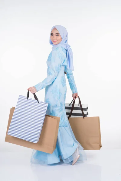 白い背景に隔離されたショッピングバッグを運ぶアジアの伝統的なドレス現代のクルンの美しいイスラム教徒の女性モデル Eidul Fitriお祝いの準備ショッピングコンセプト 全長像 — ストック写真