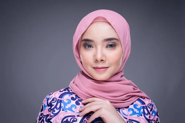 Beautiful Muslim female model wearing modern apparel with hijab, a urban lifestyle apparel for Muslim women isolated on grey background. Beauty and hijab fashion concept. Headshot portrait.