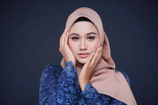 Closeup of a beautiful female Muslim model wearing dark blue modern kurung with hijab, a modern urban lifestyle apparel for Muslim women isolated on grey background. Beauty and hijab fashion concept.