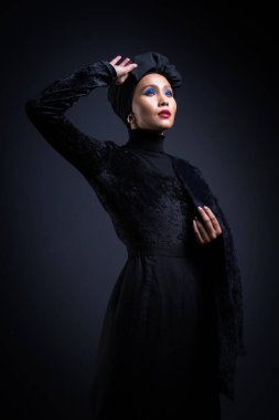 Siyah bluzlu ve gri arka planda türbanı olan Asyalı bir kadının yüksek moda portresi. Başörtüsü modası için moda editörlüğü konsepti. Yarım uzunluk