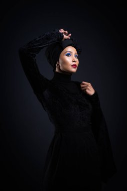 Siyah bluzlu ve gri arka planda türbanı olan Asyalı bir kadının yüksek moda portresi. Başörtüsü modası için moda editörlüğü konsepti. Yarım uzunluk