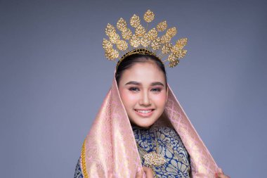 Geleneksel dans kıyafeti giymiş güzel bir Malezyalı kadın dansçının portresi ve büyüleyici bir gülümseme. Gri renkte izole edilmiş.