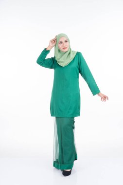 Modern Kurung ve tesettüre sahip güzel bir kadın modeli, beyaz arka planda izole edilmiş Müslüman kadınlar için modern bir yaşam tarzı. Güzellik ve tesettür moda konsepti. Tam boy portre