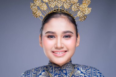 Geleneksel dans kıyafeti giymiş güzel bir Malezyalı kadın dansçının portresi ve büyüleyici bir gülümseme. Gri renkte izole edilmiş.