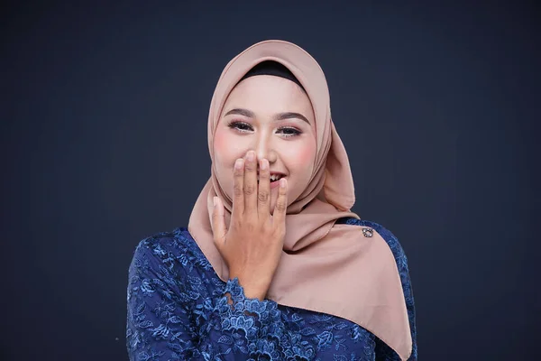 Closeup of a beautiful female Muslim model wearing dark blue modern kurung with hijab, a modern urban lifestyle apparel for Muslim women isolated on grey background. Beauty and hijab fashion concept.