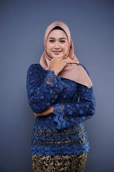 Attractive female Muslim model wearing dark blue modern kurung with hijab, a modern urban lifestyle apparel for Muslim women isolated on grey background. Beauty and hijab fashion concept.