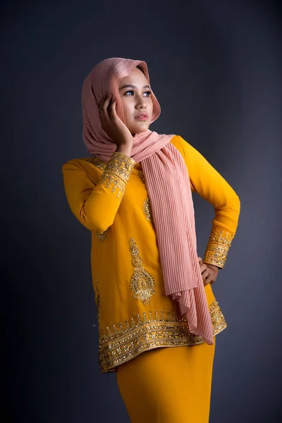 Beautiful female Muslim model in various poses wearing modern kurung and hijab, a modern lifestyle apparel for Muslim women isolated on grey background. Beauty and hijab fashion concept. Half length portrait