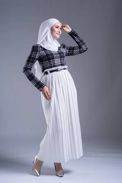 Full length portrait of a beautiful Muslim female model in a hijab and casual wear on grey background. Hijab and Muslim fashion lifestyle concept