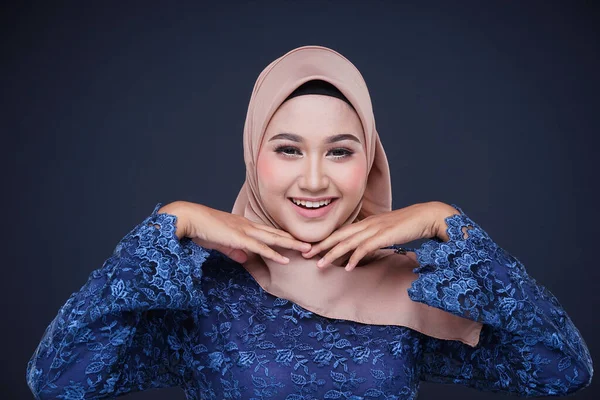 Closeup of a beautiful female Muslim model wearing dark blue modern kurung with hijab, a modern urban lifestyle apparel for Muslim women isolated on grey background. Beauty and hijab fashion concept.