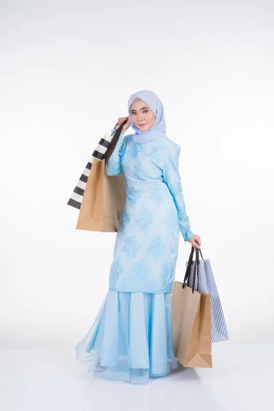 一位漂亮的穆斯林女模特穿着亚洲传统服饰 穿着时髦的和服 背着白色背景的购物袋 Eidul Fitri节庆准备购物概念 全长肖像 — 图库照片