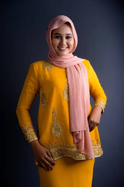 Beautiful female Muslim model in various poses wearing modern kurung and hijab, a modern lifestyle apparel for Muslim women isolated on grey background. Beauty and hijab fashion concept. Half length portrait