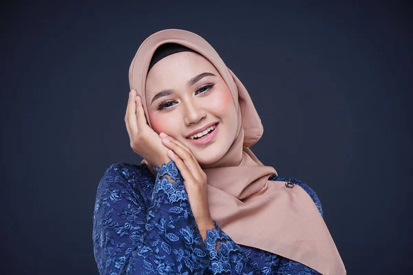 Closeup of a beautiful female Muslim model wearing dark blue modern kurung with hijab, a modern urban lifestyle apparel for Muslim women isolated on grey background. Beauty and hijab fashion concept.