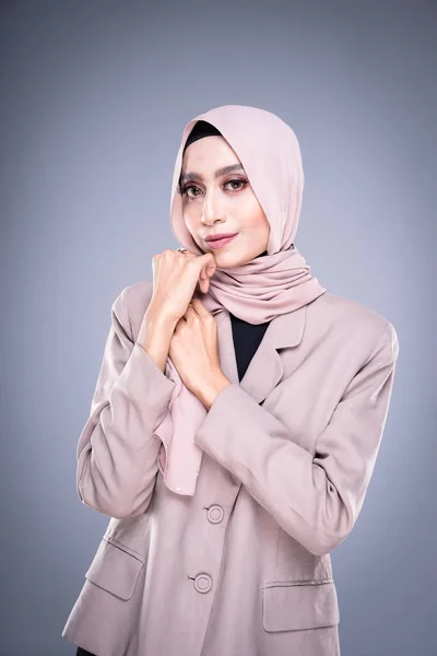 Half length portrait of a beautiful Muslim female model in a hijab and officewear isolated on grey background. Hijab and Muslim fashion lifestyle concept