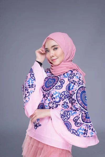 Beautiful Muslim female model wearing modern apparel with hijab, a urban lifestyle apparel for Muslim women isolated on grey background. Beauty and hijab fashion concept. Half length