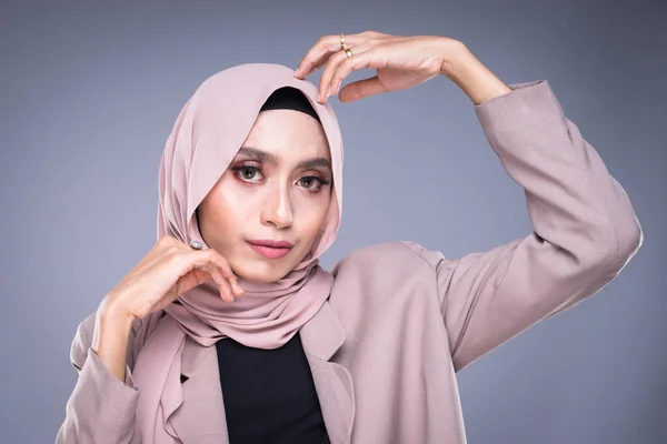 Headshot of a beautiful Muslim female model in a hijab and officewear isolated on grey background. Hijab and Muslim fashion lifestyle concept