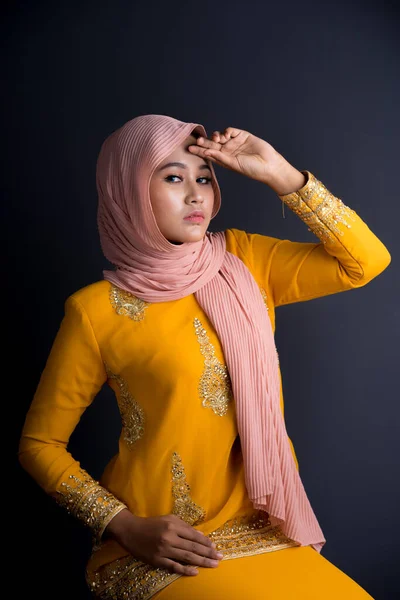 Beautiful female Muslim model in various poses wearing modern kurung and hijab, a modern lifestyle apparel for Muslim women isolated on grey background. Beauty and hijab fashion concept. Half length portrait