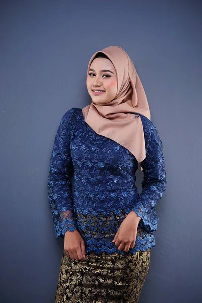Attractive female Muslim model wearing dark blue modern kurung with hijab, a modern urban lifestyle apparel for Muslim women isolated on grey background. Beauty and hijab fashion concept.
