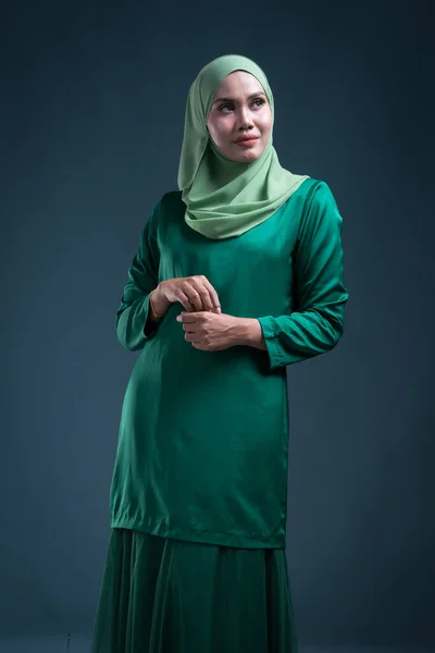 緑の背景にイスラム教徒の女性のための都市生活のアパレルである現代のクルンとヒジャーブの美しい女性のイスラム教徒モデルの半長の肖像画 美とヒジャーブファッションの肖像コンセプト — ストック写真