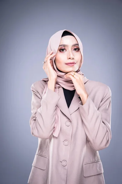 Half length portrait of a beautiful Muslim female model in a hijab and officewear isolated on grey background. Hijab and Muslim fashion lifestyle concept