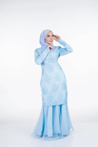 Attractive Muslim female model wearing pastel blue modern kurung with hijab, a urban lifestyle apparel for Muslim women isolated on white background. Beauty and hijab fashion concept. Full length