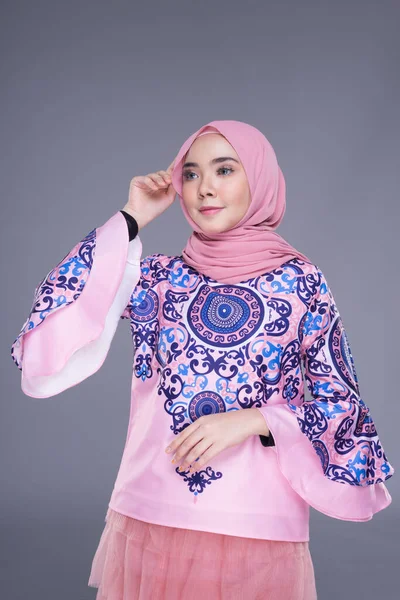 Beautiful Muslim female model wearing modern apparel with hijab, a urban lifestyle apparel for Muslim women isolated on grey background. Beauty and hijab fashion concept. Half length