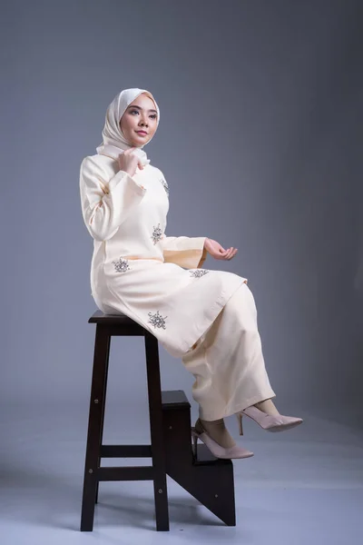 Beautiful female Muslim model wearing kurung Pahang and hijab, an urban lifestyle apparel for Muslim women on grey. Beauty and hijab fashion concept. Full length portrait