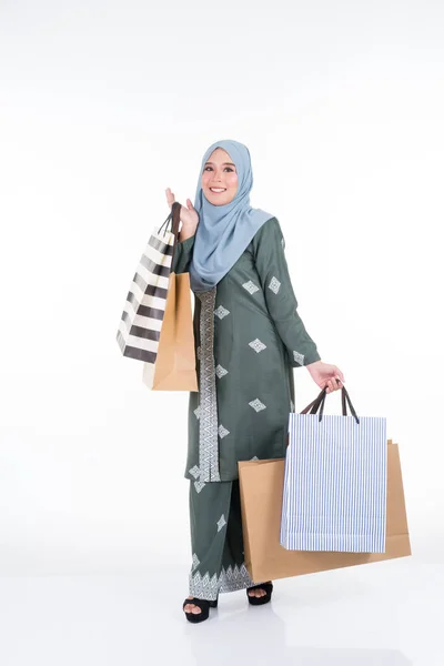 一位美丽而兴奋的穆斯林女模特穿着亚洲传统服装 身穿现代木瓜 提着白色背景的购物袋 Eidul Fitri时尚和节日准备购物概念 — 图库照片
