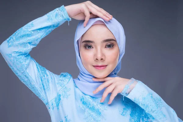 Headshot portrait of a beautiful Muslim female model in a pastel blue hijab, an Asian Muslim traditional isolated on grey background. Eidul fitri fashion and lifestyle portrait concept.