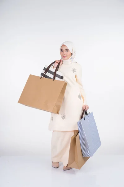 一位漂亮的穆斯林女模特穿着亚洲传统服饰 背着白色背景的购物袋 Eidul Fitri节庆准备购物概念 全长肖像 — 图库照片