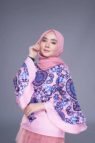 Beautiful Muslim female model wearing modern apparel with hijab, a urban lifestyle apparel for Muslim women isolated on grey background. Beauty and hijab fashion concept. Half length