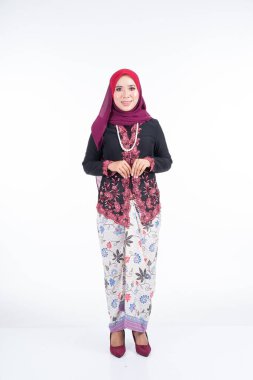 Geleneksel elbise ve tesettüre bürünmüş güzel bir kadın modelin tam boy portresi, gri arka planda yaşayan Müslüman kadınlar için bir yaşam tarzı. Idul Fitri ve tesettür moda konsepti.