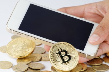 Fintech, iş ve kripto para birimi konsepti. Akıllı telefonlu bir yığın altın para ve beyaz arka planda Bitcoin.