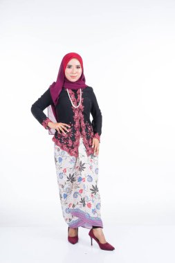 Geleneksel elbise ve tesettüre bürünmüş güzel bir kadın modelin tam boy portresi, gri arka planda yaşayan Müslüman kadınlar için bir yaşam tarzı. Idul Fitri ve tesettür moda konsepti.