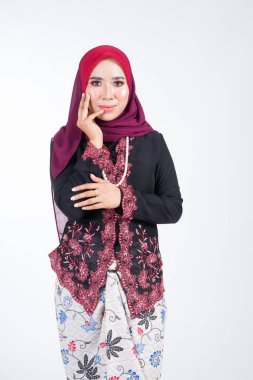 Geleneksel elbise ve tesettüre bürünmüş güzel bir kadın modelin yarım boy portresi, beyaz arka planda izole edilmiş Müslüman kadınlar için bir yaşam tarzı. Idul Fitri ve tesettür moda konsepti.